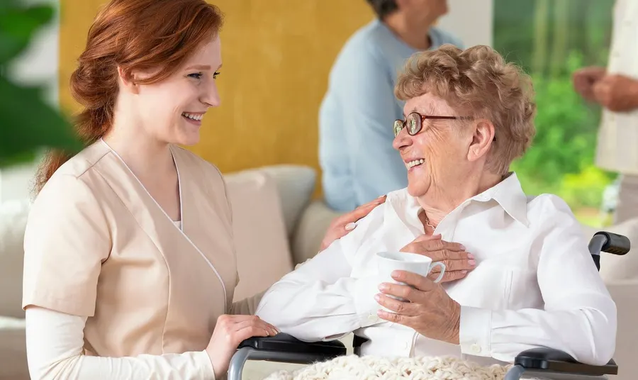 Betreuerin und ältere Dame mit Kaffeetasse im Gespräch